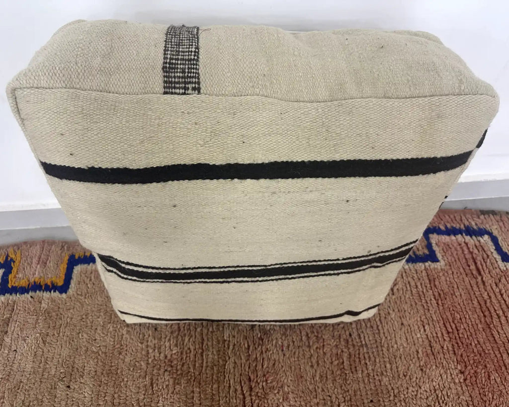 Handmade Moroccan kilim pouf featuring minimalist woven stripe bands, flatwoven Berber textile construction, and artisan handcrafted detailing.