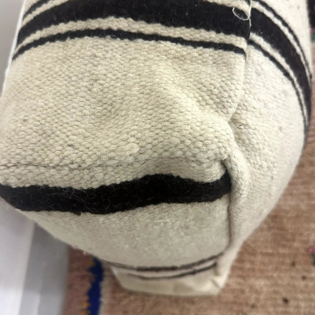 Handmade Moroccan kilim pouf featuring vertical stripe motifs, flatwoven Berber textile construction, and artisan handcrafted detailing.