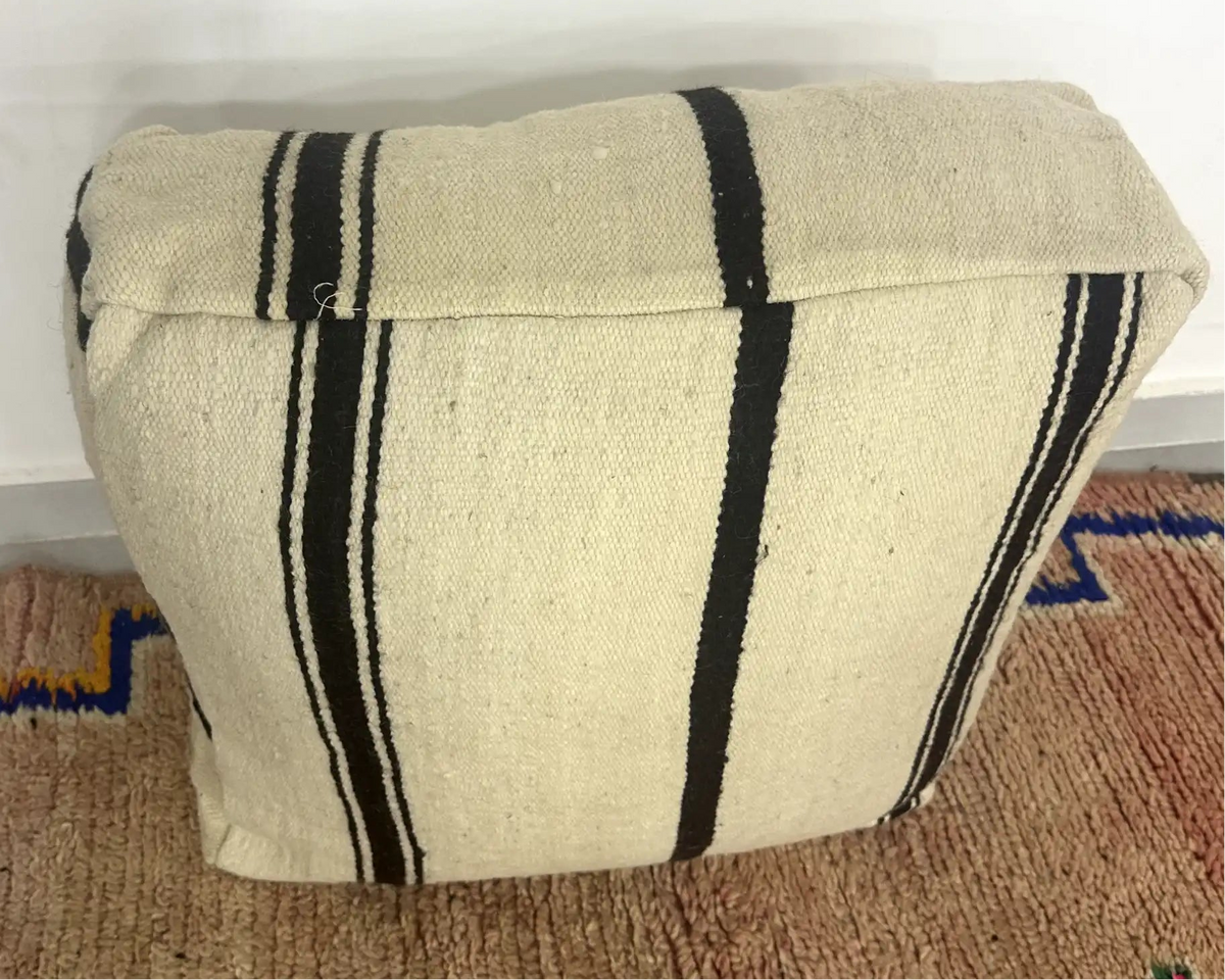 Handmade Moroccan kilim pouf featuring vertical stripe motifs, flatwoven Berber textile construction, and artisan handcrafted detailing.