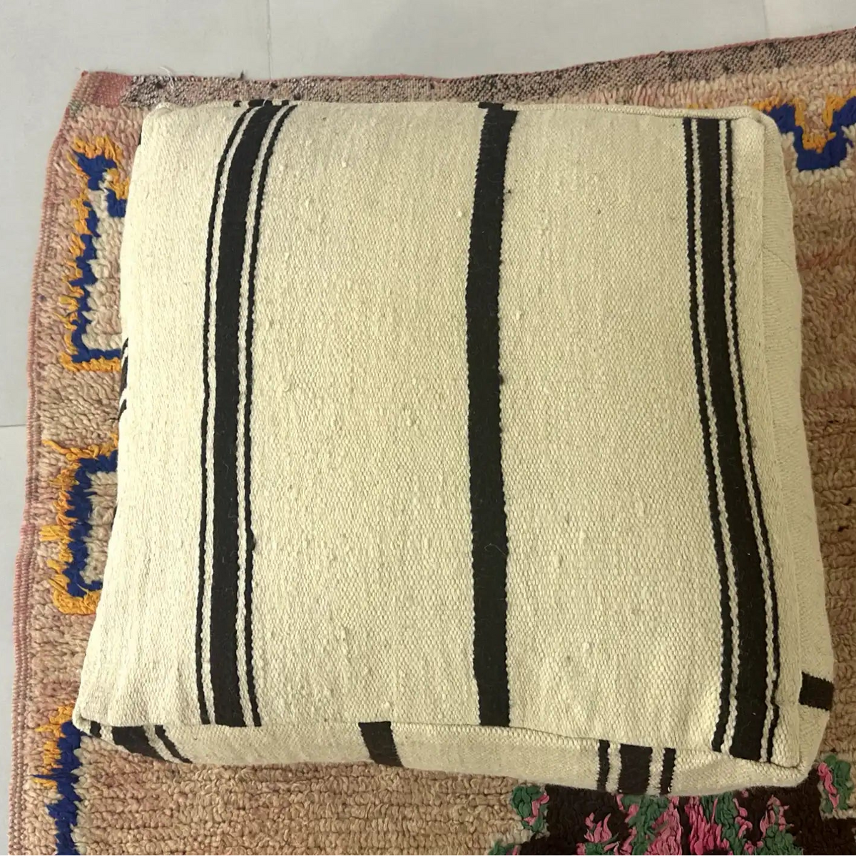 Handmade Moroccan kilim pouf featuring vertical stripe motifs, flatwoven Berber textile construction, and artisan handcrafted detailing.